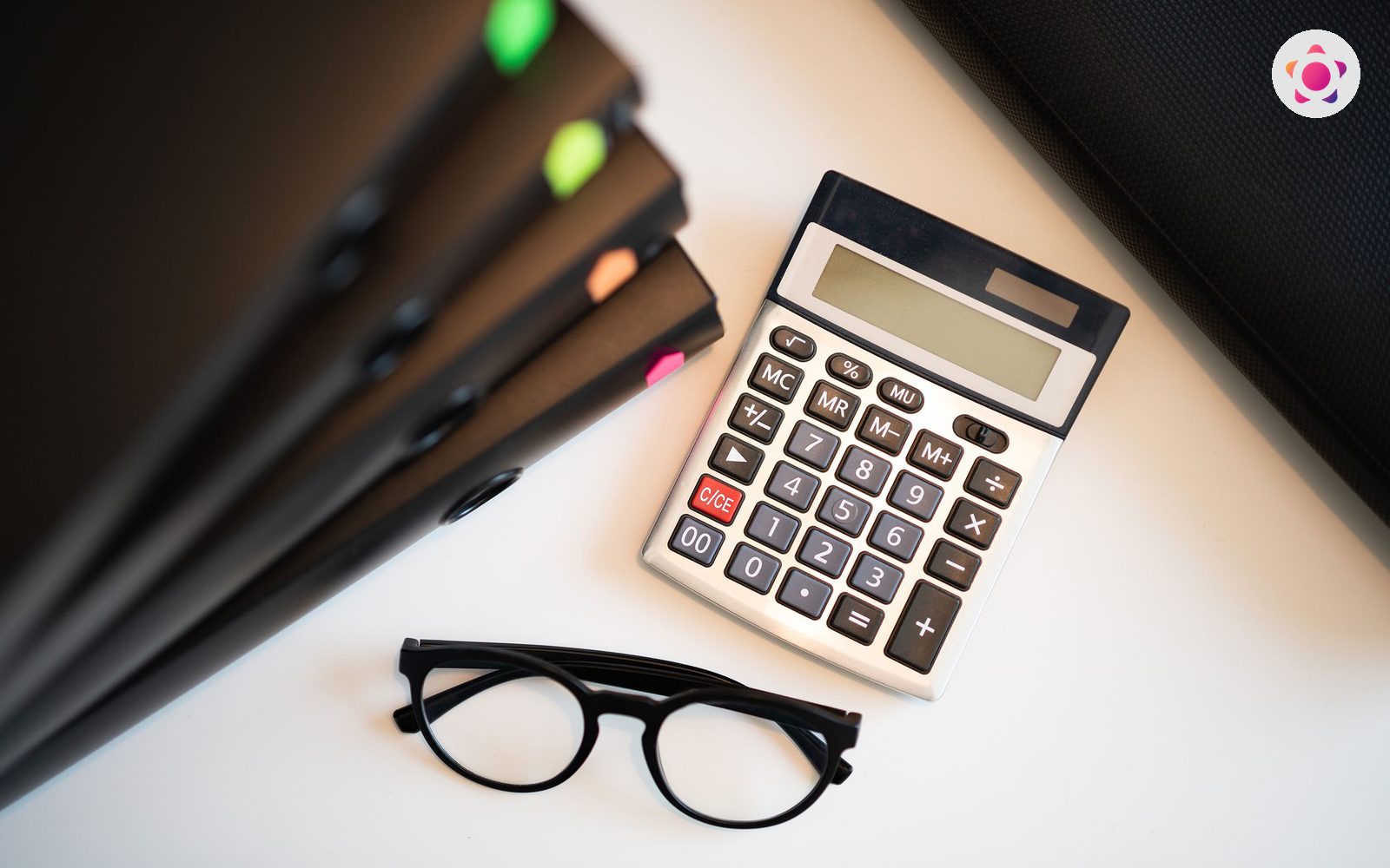 Calculator, ochelari si dosare pe un birou, pentru calculul taxei judiciare de timbru
